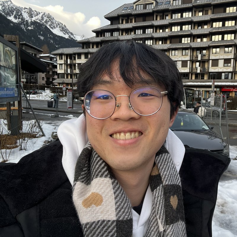 Shih Ee, smiling, in a scarf in front of snowy mountains